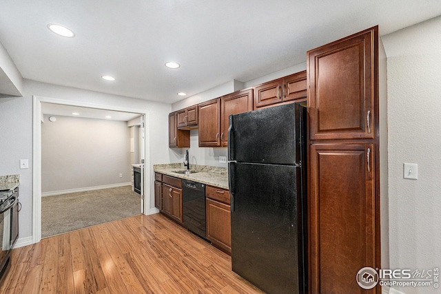 kitchen featuring a sink, black appliances, recessed lighting, baseboards, and light wood-style floors