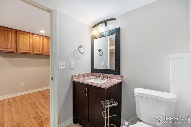 bathroom featuring toilet, baseboards, vanity, and wood finished floors