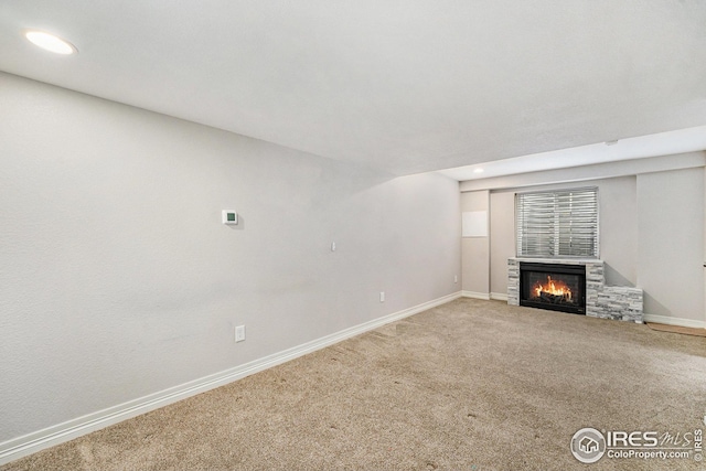 unfurnished living room featuring carpet flooring, baseboards, a stone fireplace, and recessed lighting
