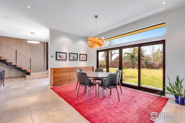dining space with tile patterned floors, wood walls, recessed lighting, and stairway