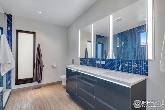 bathroom with a sink, visible vents, baseboards, and decorative backsplash