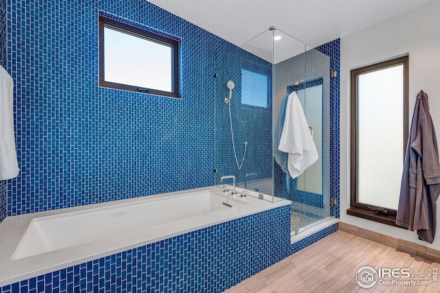 bathroom with a bath, a stall shower, and wood finished floors