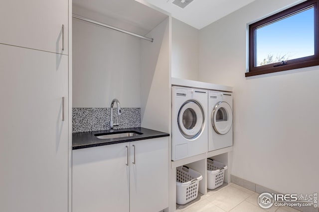 washroom featuring separate washer and dryer, baseboards, tile patterned flooring, cabinet space, and a sink