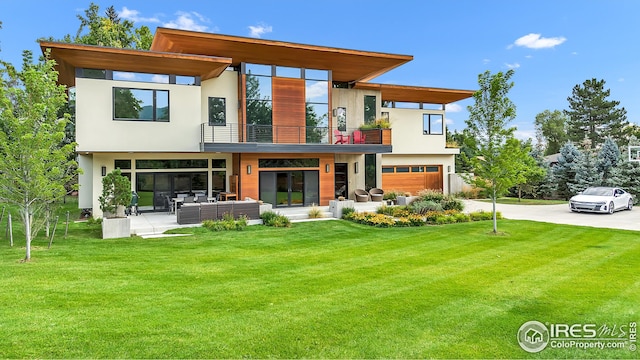 rear view of house with an outdoor hangout area, stucco siding, a lawn, a balcony, and an attached garage