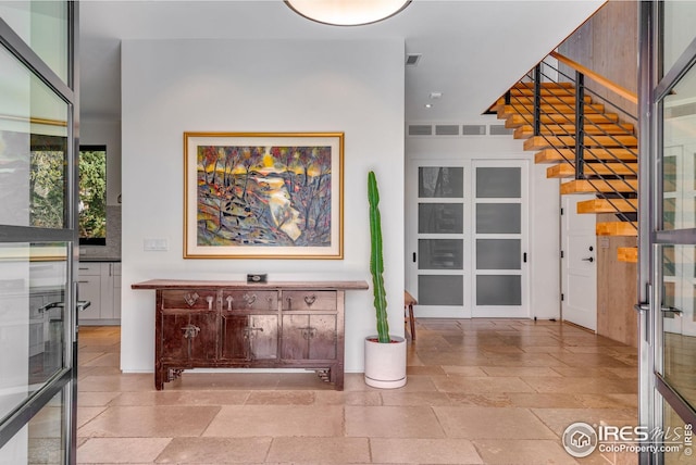 entryway with stairway, visible vents, french doors, and stone tile flooring