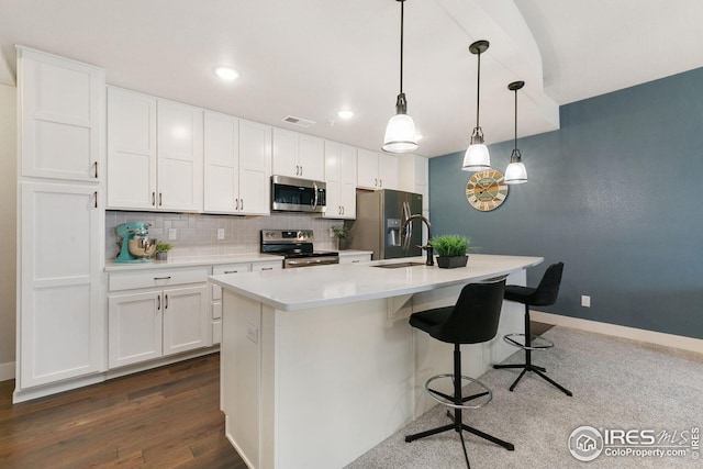kitchen with visible vents, a kitchen bar, white cabinetry, stainless steel appliances, and backsplash