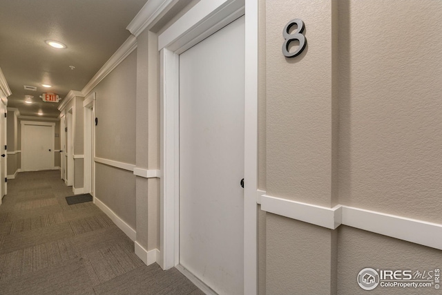 hall with a textured wall, carpet, and crown molding