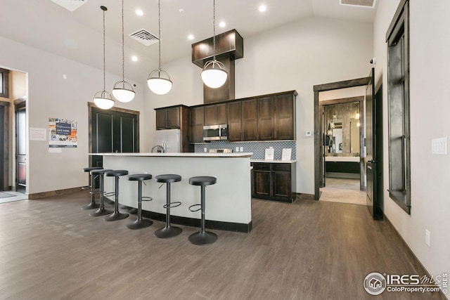 kitchen featuring dark brown cabinets, a kitchen island with sink, visible vents, dark wood finished floors, and appliances with stainless steel finishes