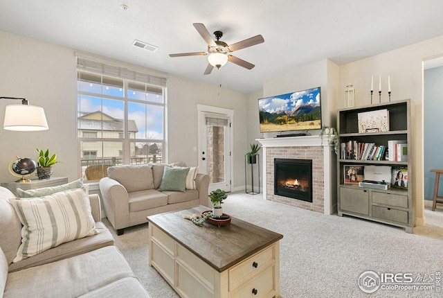living area with visible vents, a brick fireplace, a ceiling fan, and light carpet
