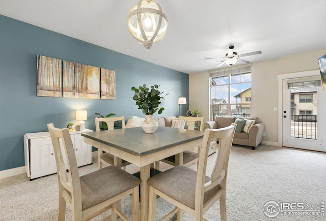 dining room with ceiling fan, light colored carpet, and baseboards