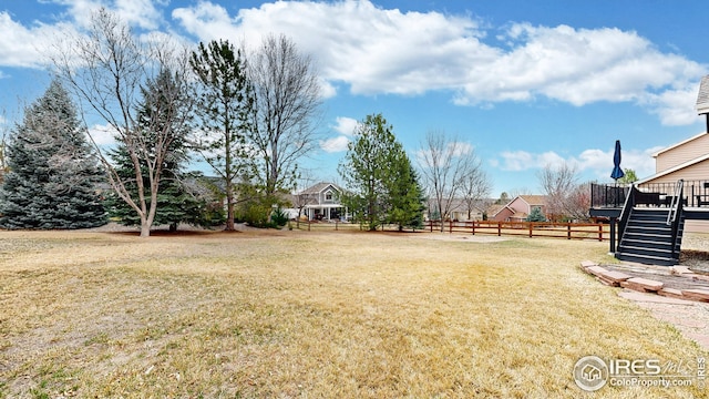 view of yard featuring fence, a wooden deck, and stairs