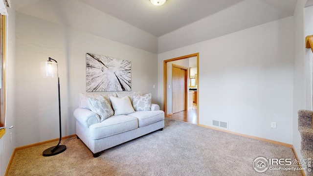 living area with carpet flooring, baseboards, vaulted ceiling, and visible vents