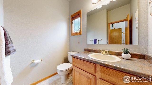 bathroom with toilet, vanity, and baseboards