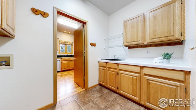 kitchen featuring tile countertops, stainless steel dishwasher, and baseboards