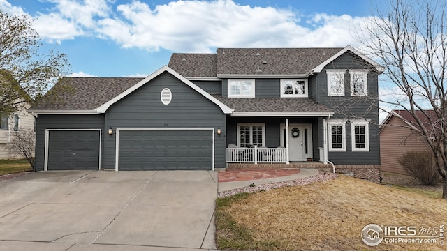 traditional-style house with a shingled roof, covered porch, a garage, and concrete driveway