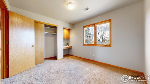 unfurnished bedroom featuring light colored carpet, visible vents, a closet, and baseboards