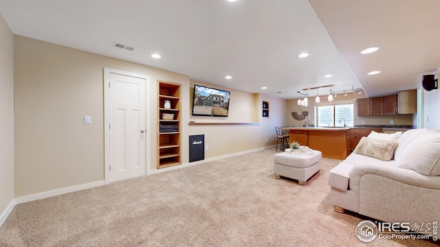 living room featuring visible vents, baseboards, built in features, recessed lighting, and light colored carpet