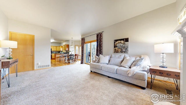 living room featuring visible vents, light colored carpet, and baseboards