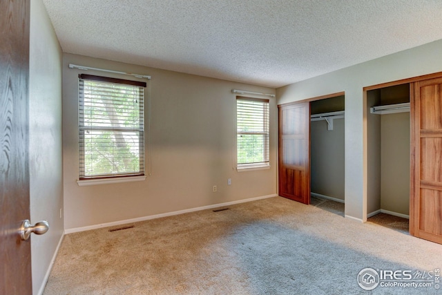 2924 Ross Dr Unit H20, Fort Collins, CO 80526 - unfurnished bedroom featuring carpet floors, a textured ceiling, visible vents, and multiple closets
