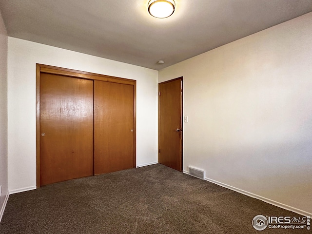 unfurnished bedroom with carpet, visible vents, and a closet