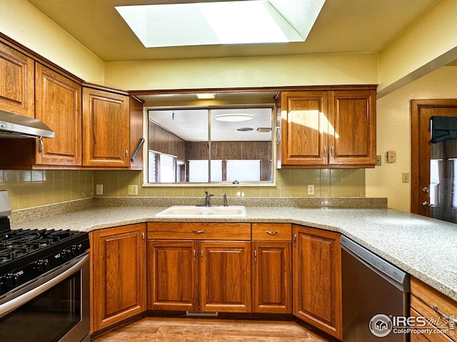 1401 Constitution Ave, Fort Collins, CO 80521 - kitchen featuring a sink, appliances with stainless steel finishes, brown cabinetry, backsplash, and a skylight