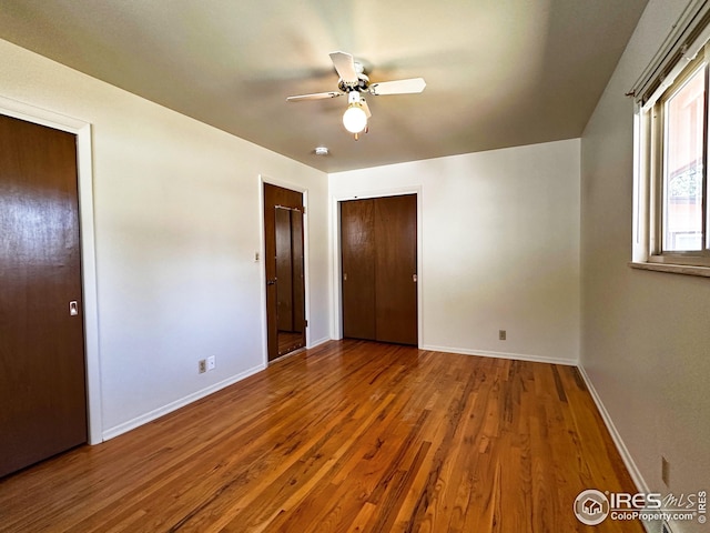 1401 Constitution Ave, Fort Collins, CO 80521 - unfurnished bedroom with wood finished floors, baseboards, a ceiling fan, and multiple closets