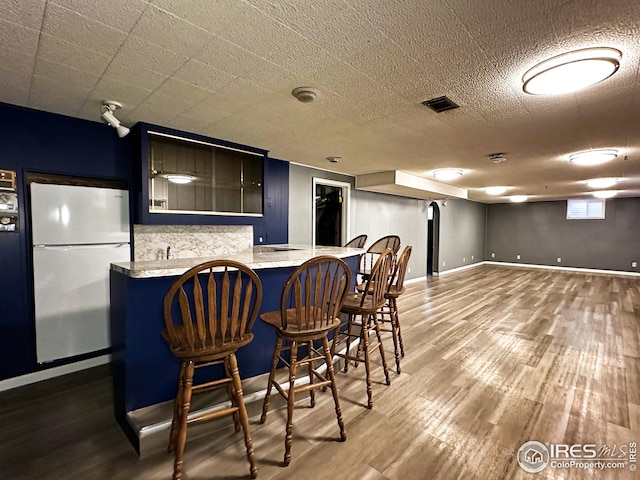 1401 Constitution Ave, Fort Collins, CO 80521 - kitchen with a kitchen breakfast bar, freestanding refrigerator, visible vents, decorative backsplash, and wood finished floors
