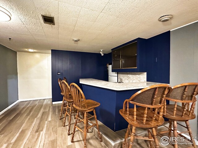 1401 Constitution Ave, Fort Collins, CO 80521 - bar with baseboards, refrigerator, wet bar, visible vents, and wood finished floors