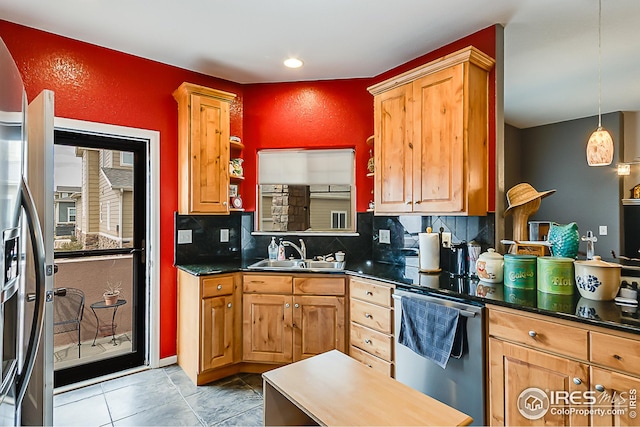 kitchen featuring a sink, appliances with stainless steel finishes, dark countertops, backsplash, and a textured wall