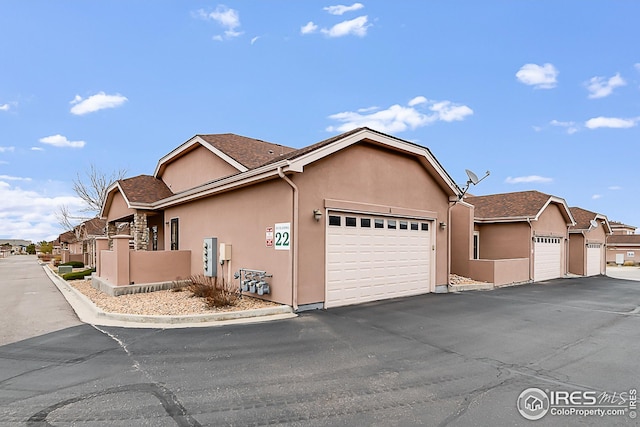 view of side of property with a garage, stucco siding, and asphalt driveway
