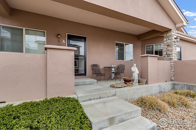 doorway to property with stucco siding and fence