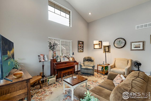 living room featuring high vaulted ceiling and baseboards