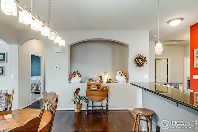 dining room featuring dark wood-style flooring, baseboards, and arched walkways