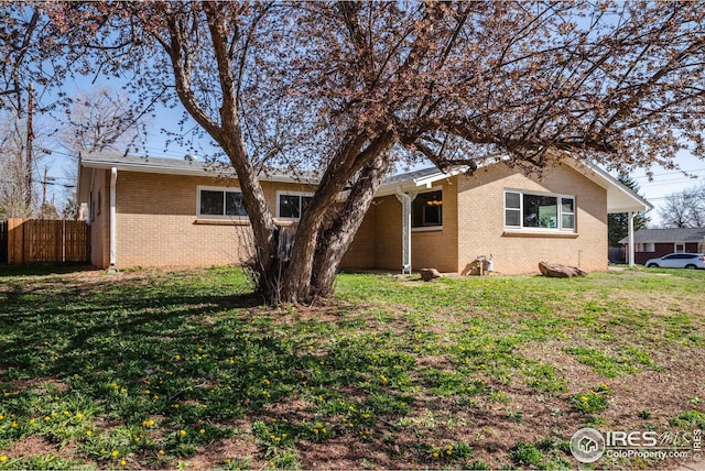 back of property featuring a yard, brick siding, and fence