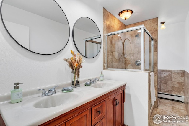 bathroom featuring a shower stall, a baseboard radiator, double vanity, and a sink