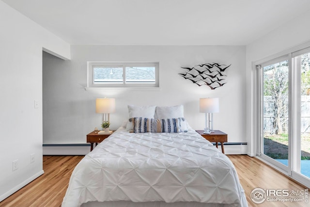 bedroom featuring baseboard heating, access to exterior, and light wood finished floors