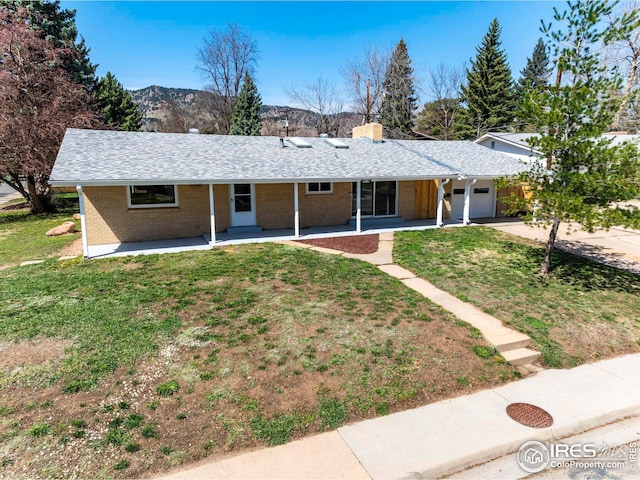 ranch-style home featuring a front lawn, brick siding, an attached garage, a chimney, and concrete driveway