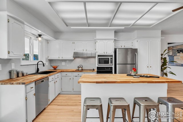 kitchen featuring butcher block countertops, a sink, white cabinetry, and stainless steel appliances