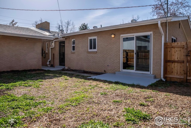 rear view of property with a patio area, brick siding, a yard, and fence