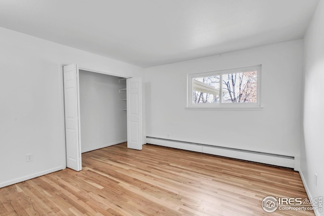 unfurnished room with light wood-style flooring and a baseboard radiator