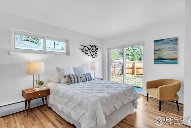 bedroom featuring a baseboard radiator, access to outside, and light wood-style floors