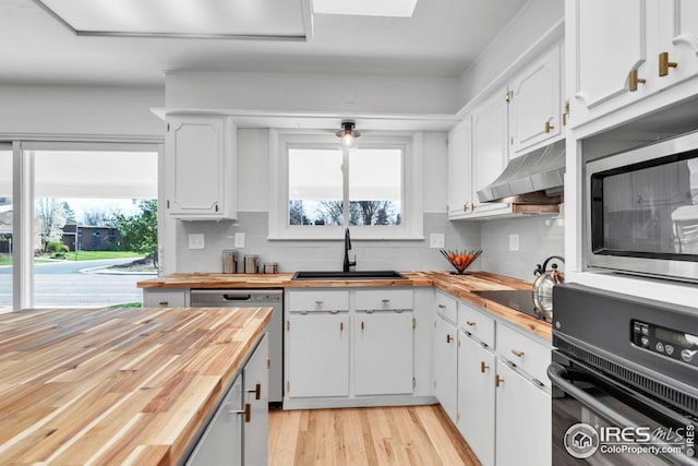 kitchen with a sink, butcher block countertops, black appliances, and under cabinet range hood