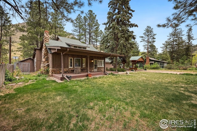 198 Poudre River Rd, Bellvue, CO 80512 - rear view of property featuring fence, a chimney, a lawn, and stone siding