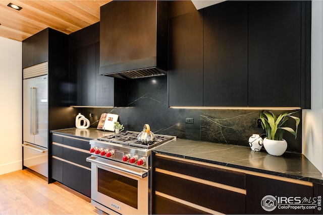 kitchen with premium range hood, high quality appliances, decorative backsplash, and dark cabinets