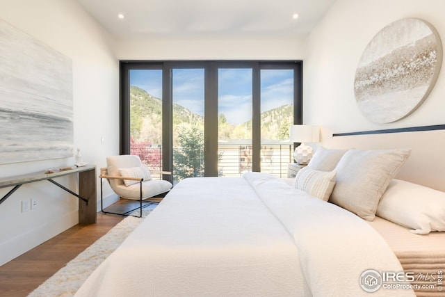bedroom featuring recessed lighting, wood finished floors, baseboards, and a mountain view