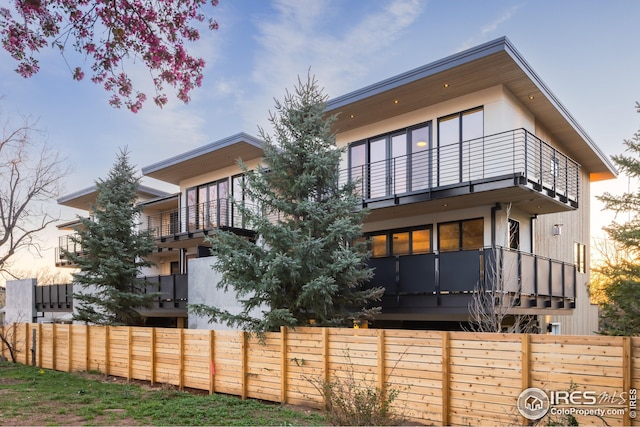 rear view of house featuring fence and a balcony