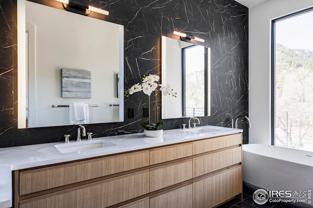 bathroom with decorative backsplash, double vanity, a sink, and a freestanding bath