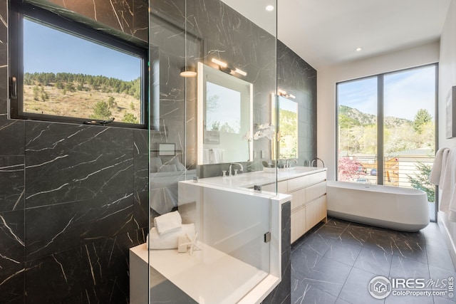 bathroom with a sink, marble finish floor, a soaking tub, double vanity, and recessed lighting