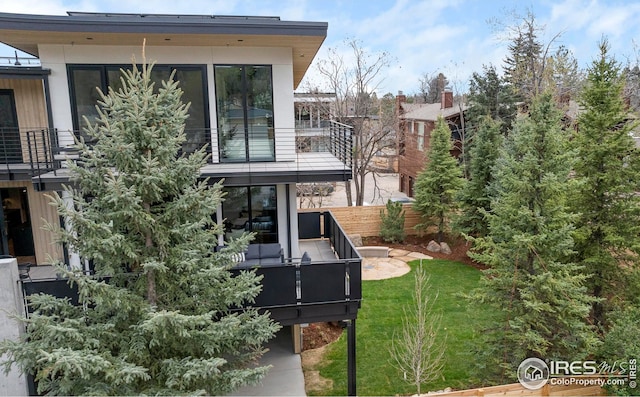 back of house featuring a yard, a balcony, and fence