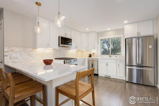 kitchen with backsplash, visible vents, appliances with stainless steel finishes, a peninsula, and white cabinetry